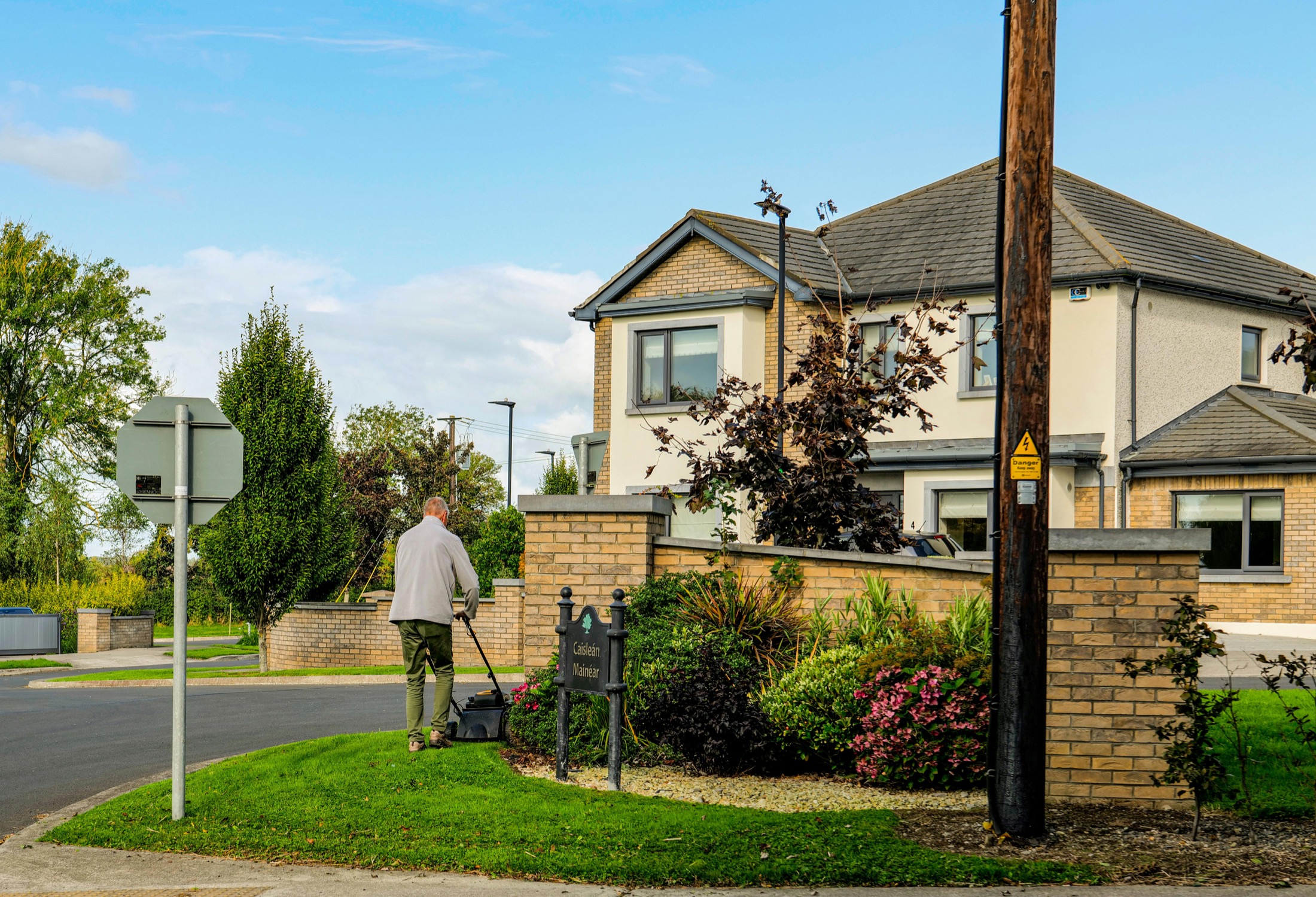 Landscaper mowing and edging a neatly maintained residential corner lot